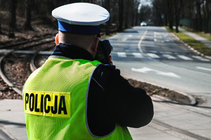 Na zdjęciu policjant wykonuje pomiar prędkości pojazdu w rejonie przejścia dla pieszych