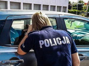 Policjantka zagląda przez szybę do samochodu.