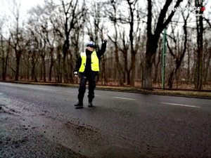 Na zdjęciu policjant zatrzymuje samochód do kontroli.