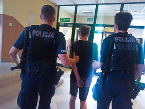 Policjanci prowadza zatrzymanego mężczyznę