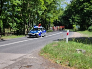 Zdjęcia kolorowe przedstawiające oznakowane pojazdy służbowe Policji podczas zabezpieczenia przejazdu rowerzystów.