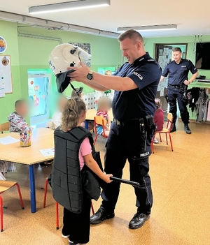 Zdjęcia kolorowe przedstawiające umundurowanych policjantów podczas przeprowadzania zajęć profilaktycznych dla dzieci podczas półkolonii.