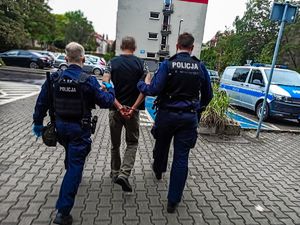 Na zdjęciu policjanci prowadzą zatrzymanego.