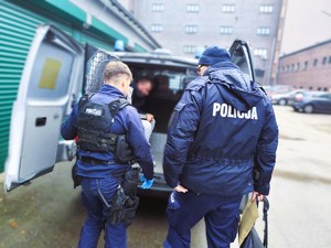 Na zdjęciu policjanci prowadzą zatrzymanego