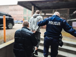 na zdjęciu policjanci prowadza zatrzymanego