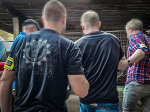 na zdjęciu policjanci prowadzą zatrzymanego