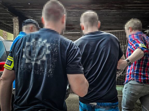 na zdjęciu policjanci prowadzą zatrzymanego