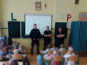 Umundurowani policjanci przeprowadzający prelekcję dla uczniów w szkole.
