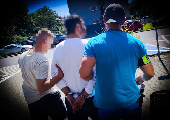 na zdjęciu policjanci prowadza zatrzymanego