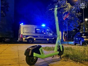 Zdjęcie kolorowe przedstawiające hulajnogę elektryczną oraz oznakowany radiowóz Policji.