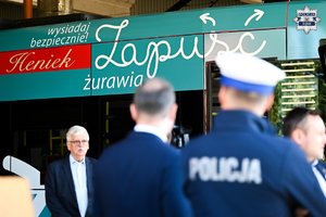Zdjęcie przedstawiające grupę osób w tym umundurowanego policjanta, stojących obok tramwaju. Na tramwaju widnieje napis &quot;wysiadaj bezpiecznie!&quot;, &quot;Heniek&quot; i &quot;Zapuść żurawia&quot;.