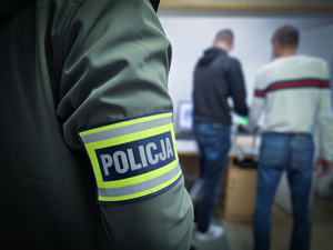 na zdjęciu policjant prowadzi zatrzymanego