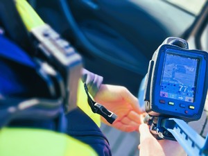 na zdjęciu policjant trzyma uprzedzenie do pomiaru prędkości