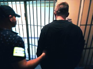 na zdjęciu policjant prowadzi zatrzymanego