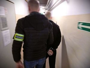 Na zdjeciu policjant prowadzi zatrzymanego