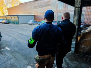 na zdjęciu policjant prowadzi zatrzymanego