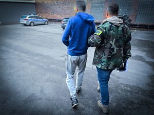 na zdjęciu policjanci za zatrzymany mężczyzną