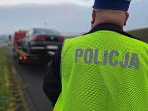 na zdjęciu policjant i samochód na lawecie