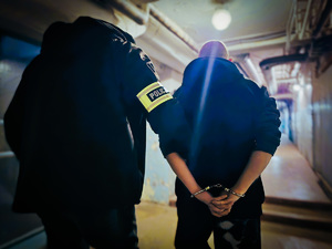 na zdjęciu nieumundurowany policjant prowadzi zatrzymanego