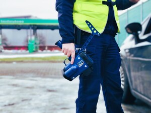 na zdjęciu policjant trzymający ręczny miernik prędkości