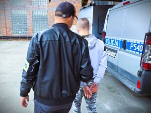 policjant prowadzi zatrzymaną osobę