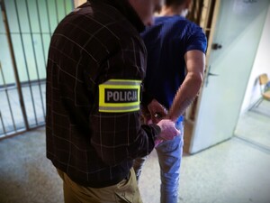 policjant prowadzi zatrzymaną osobę