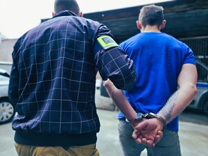 policjant prowadzi zatrzymaną osobę