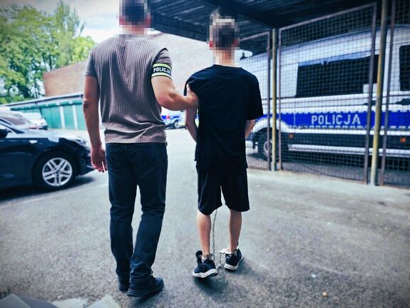 policjant prowadzi zatrzymanego